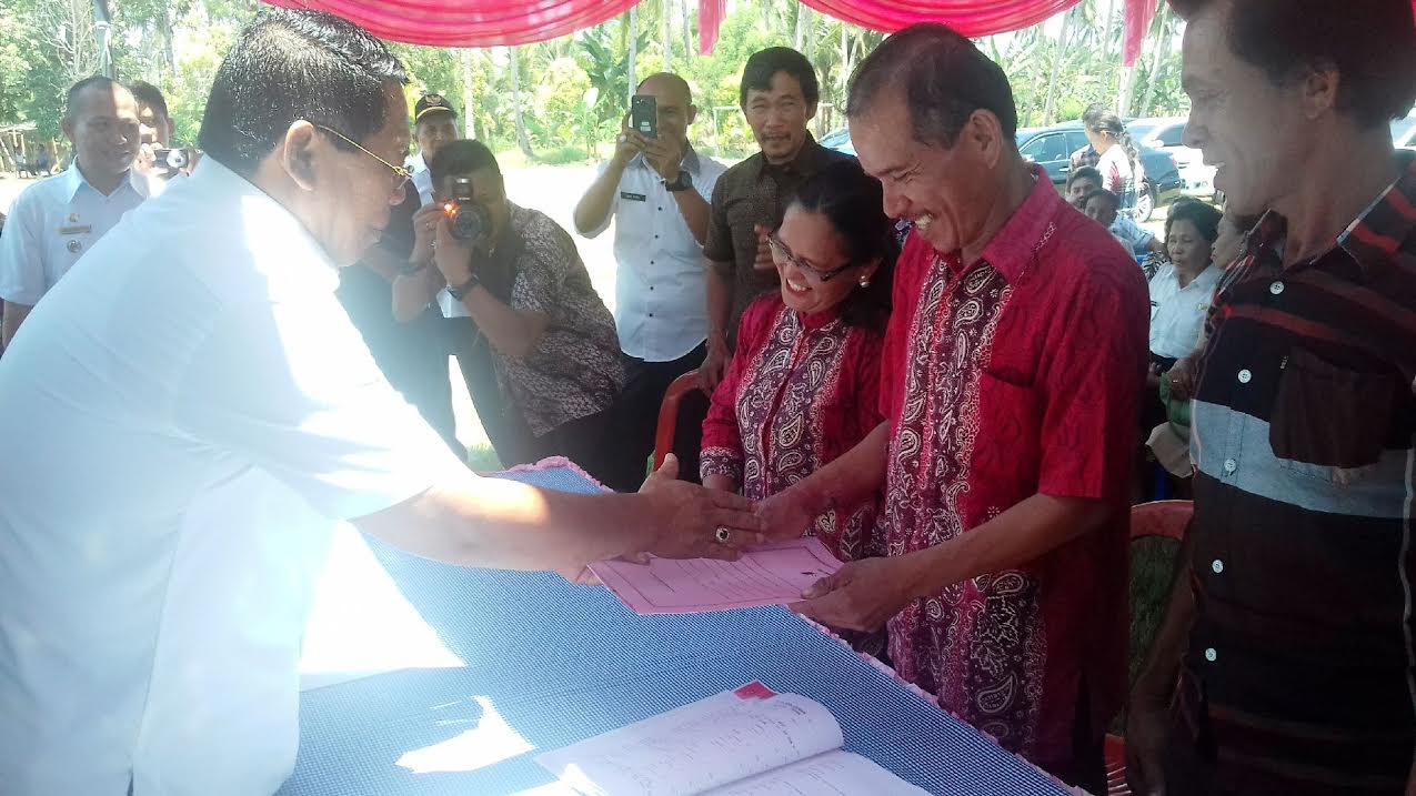 Bupati Bolmong Salihi Mokodongan menyerahkan Akta Pencatatan Perkawinan kepada pasangan suami Isteri yang mengikuti Nikah Massal. (dok Humas BM)