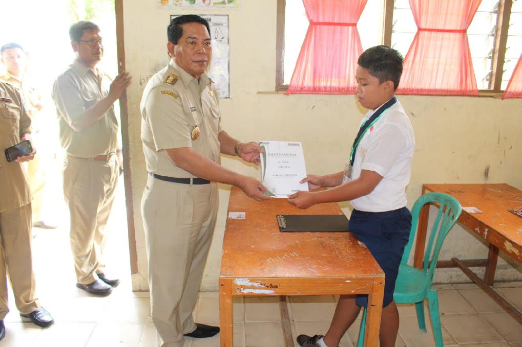 Bupati Bolmong menyerahkan secara simbolis lembaran ujian kepada salah satu siswa SMP.